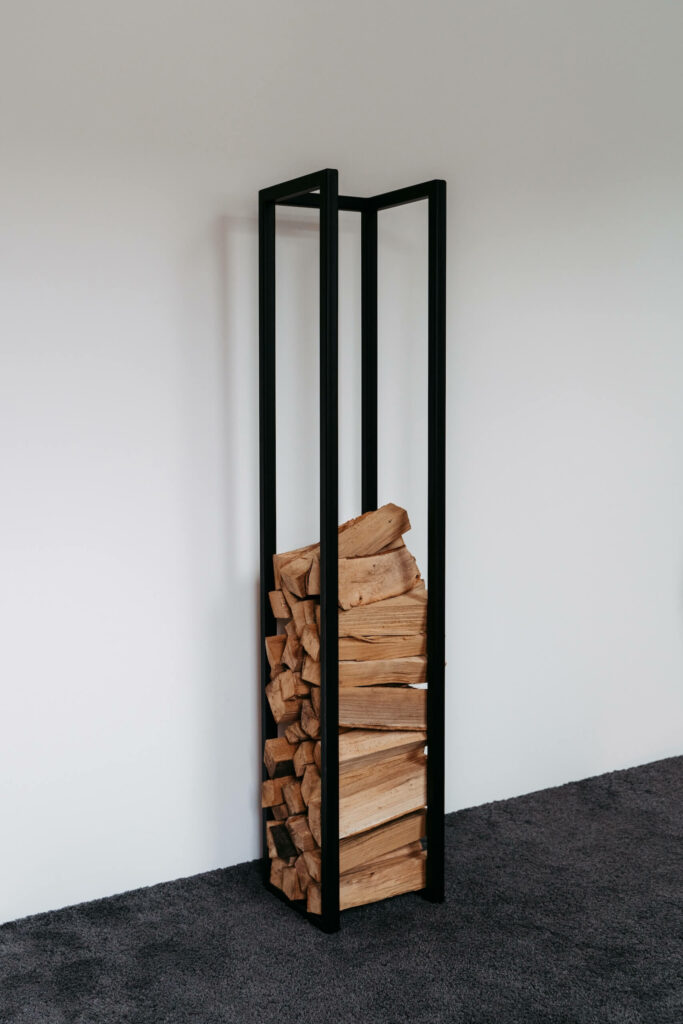Schwarze Brennholzaufbewahrung aus Stahl mit Holz darin