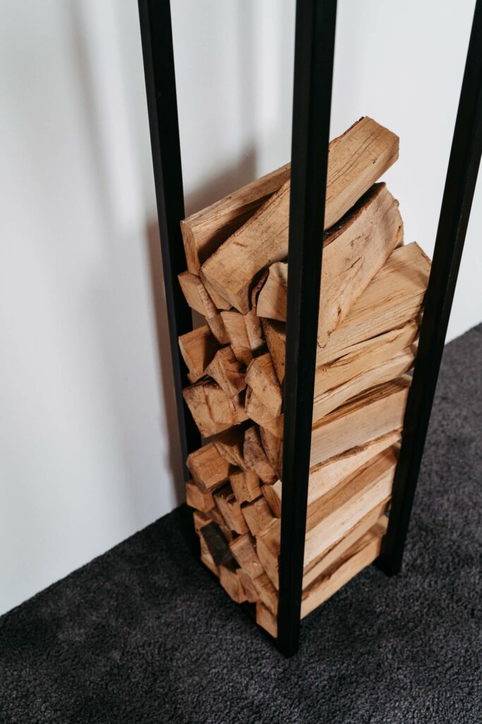 Schwarze Brennholzaufbewahrung aus Stahl mit Holz darin