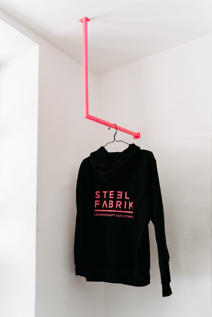 Schwarzer Pulli hängt an einer pinken Kleiderstange