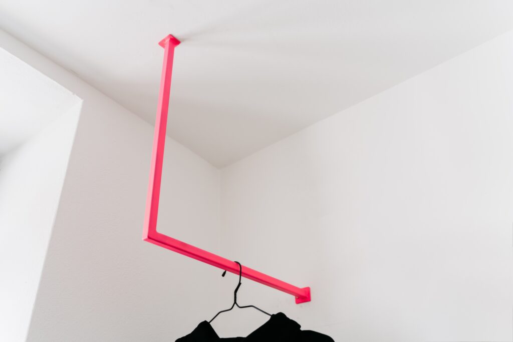 Schwarzer Pulli hängt an einer pinken Kleiderstange