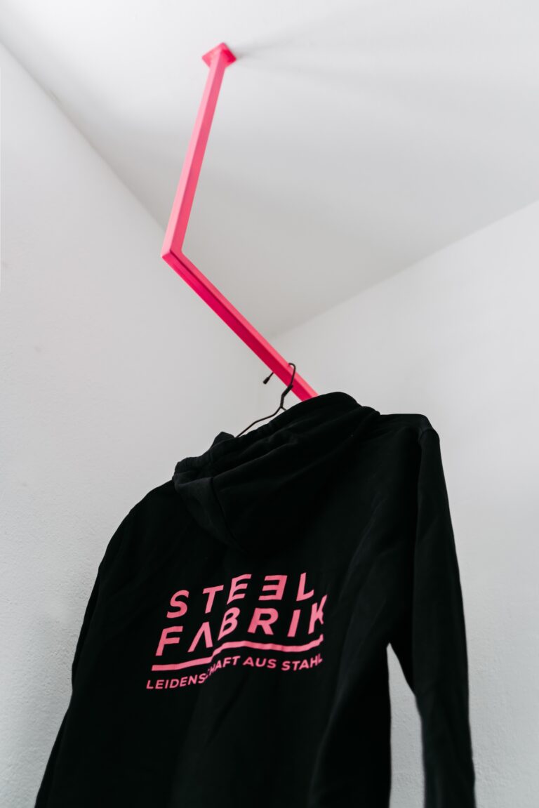 Schwarzer Pulli hängt an einer pinken Kleiderstange