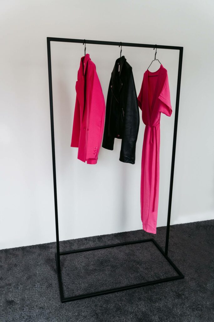 Schwarze Kleiderstange mit pinken und schwarzen Kleidungsstücken