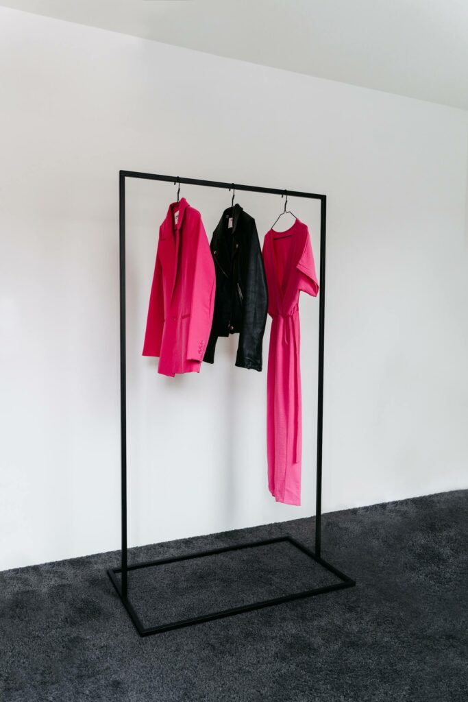 Schwarze Kleiderstange mit pinken und schwarzen Kleidungsstücken