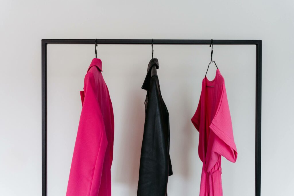 Schwarze Kleiderstange mit pinken und schwarzen Kleidungsstücken